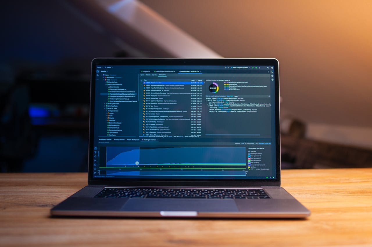 services-04 A laptop displaying code on a wooden desk, in a dimly lit workspace.