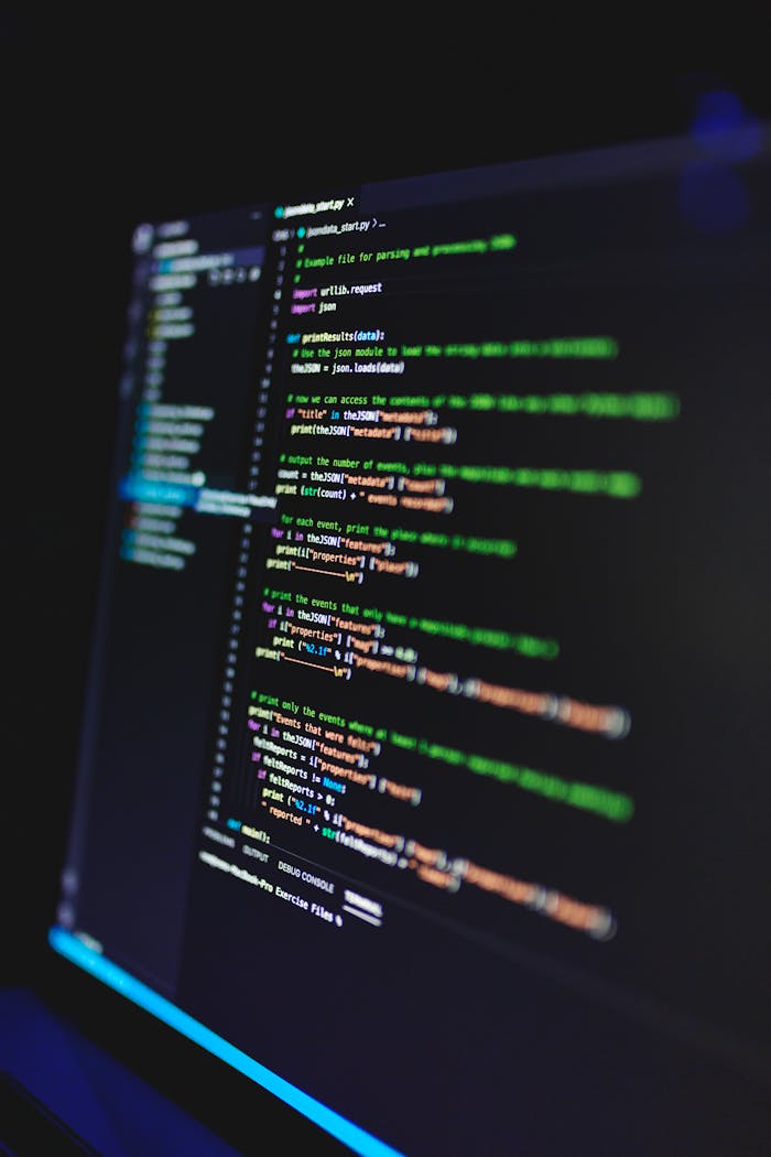 services-bg Vertical shot of colorful programming code on a screen in a dark room, highlighting technology work.